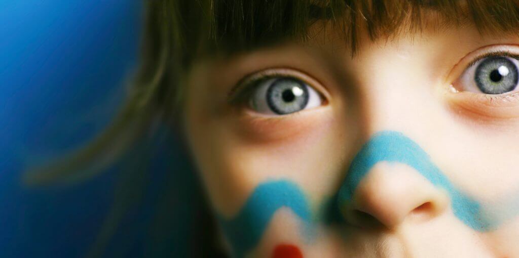 close up of girl with blue eyes and face paint