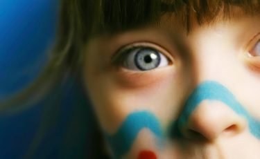 close up of girl with blue eyes and face paint
