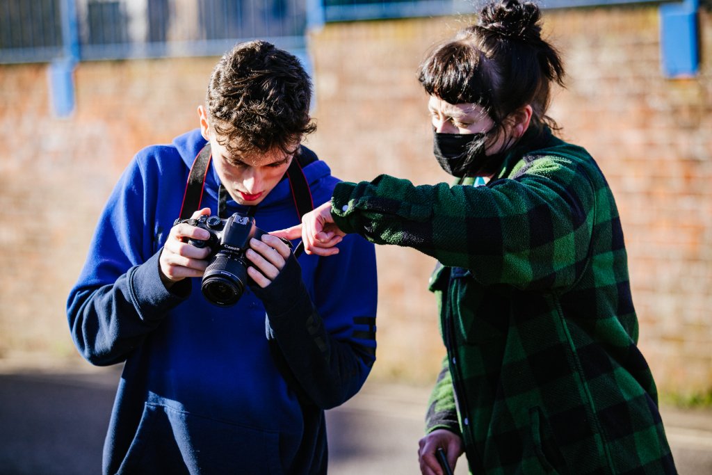 Woman showing young man how to use photographers camera
