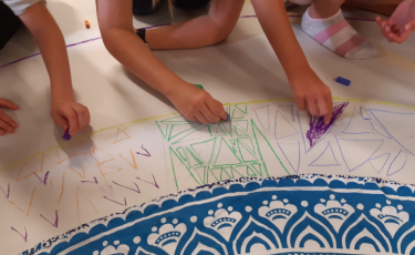 Creative workshop for families with SEND children on climate change featured image. Kids with their hands on a big white paper filled with artwork.